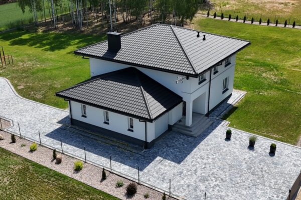 Dom otoczony nawierzchnią z szarej kostki brukowej, widok z drona